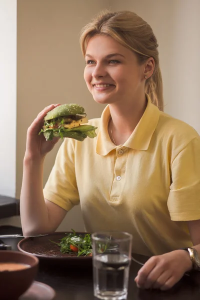 Woman eating vegan burger in restaurant