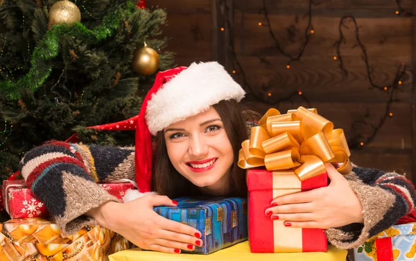 Beautiful girl sitting among many New Year presents and gifts