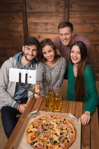 Happy friends making top view selfies in pizzeria