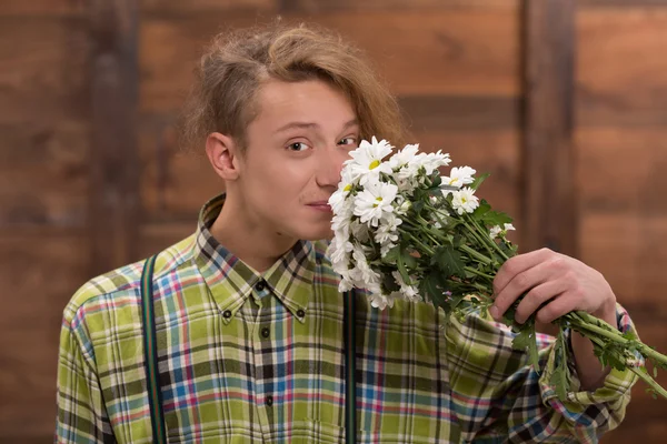Hipster man smelling bunch of flowers