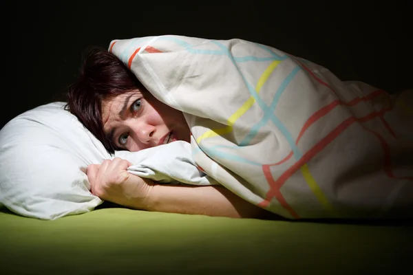 Young woman in bed with eyes opened suffering insomnia. Sleeping concept and nightmare issues