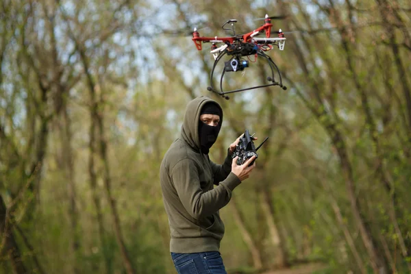 Man in mask operating a drone with remote control.
