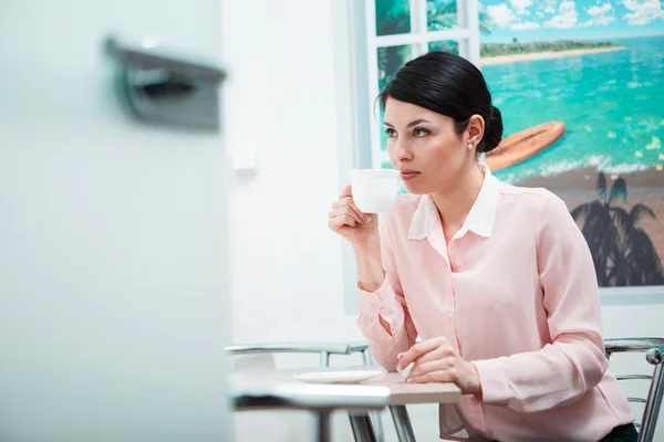 Woman drinking coffee in office kitchen