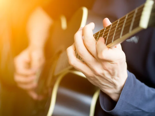 Male hand playing on acoustic guitar. Close-up.