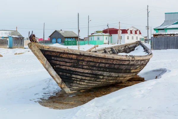 Wooden fishing boat on the winter snow-covered coast.