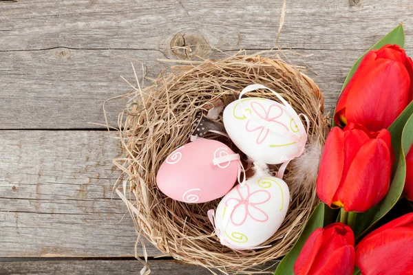 Easter eggs in nest and tulips flowers