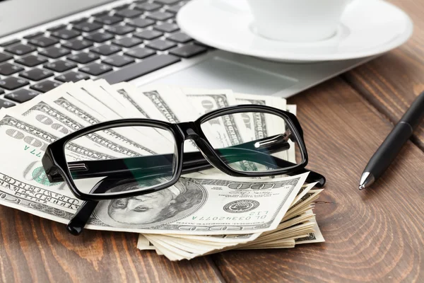 Office table with pc, coffee cup and glasses over money