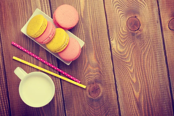 Colorful macaron cookies and cup of milk