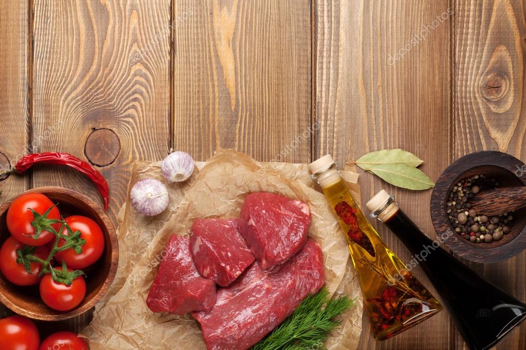 生牛肉牛排和香料木制的桌子上.