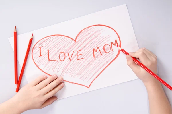 Childs hands drawing a heart that says I love mom