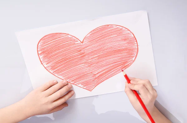 Childs hands drawing a red heart