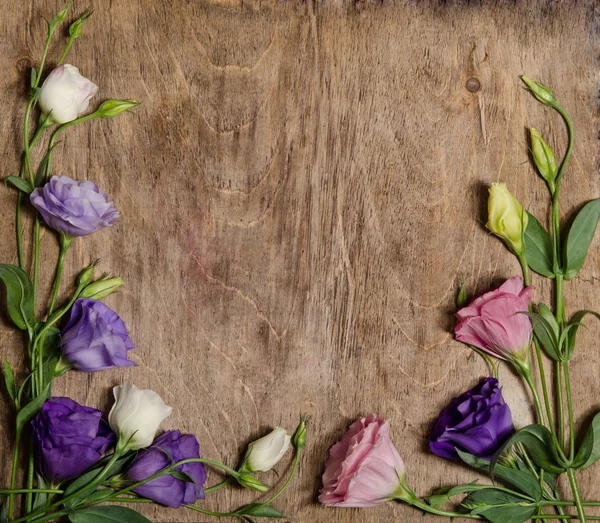 Beautiful eustoma flowers with leafs and buds on wooden backgrou
