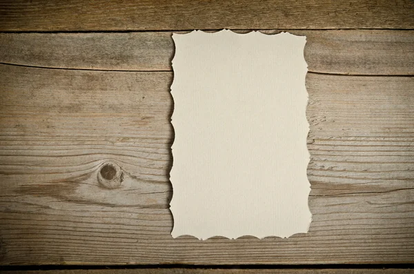 The piece of old white paper lying on a wooden background