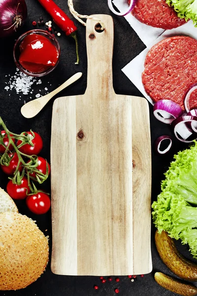 Homemade burger ingredients and empty cutting board