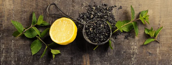 Dry tea with mint and lemon on wooden table