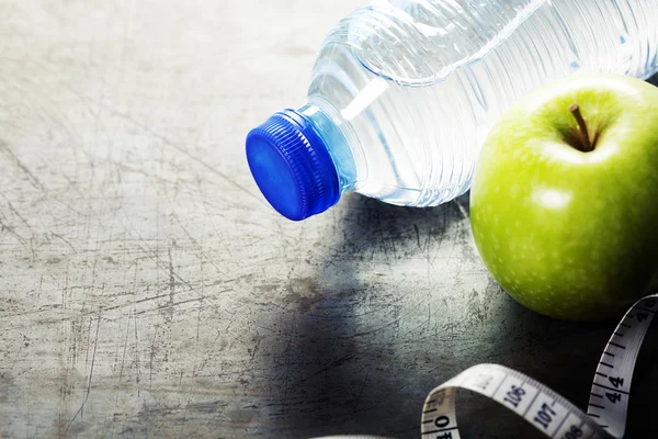 Green apple, water and measuring tape. Health and diet concept