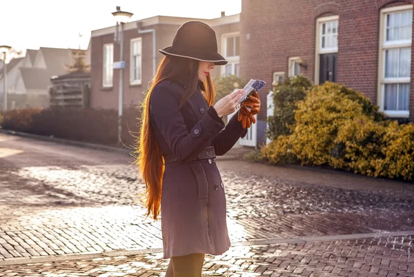 Outdoors portrait of attractive young woman with long beautiful hairs and city map in hands.