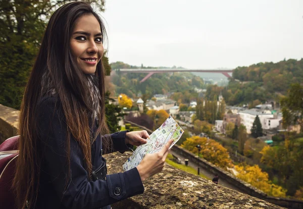 Outdoor portrait of attractive young woman with long beautiful hairs and city map on her hands.