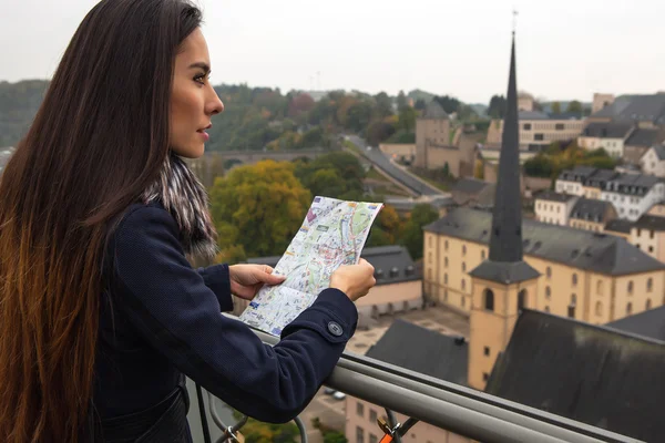 Outdoor portrait of attractive young woman with long beautiful hairs and city map on her hands.