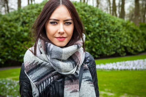 Attractive young friendly woman with long beautiful hairs posing in park.