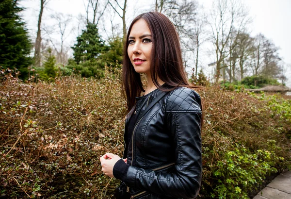 Attractive young friendly woman with long beautiful hairs posing in park.