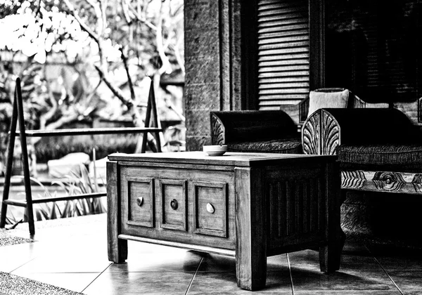 Wooden cabin with furniture on the terrace. Black-white photo.