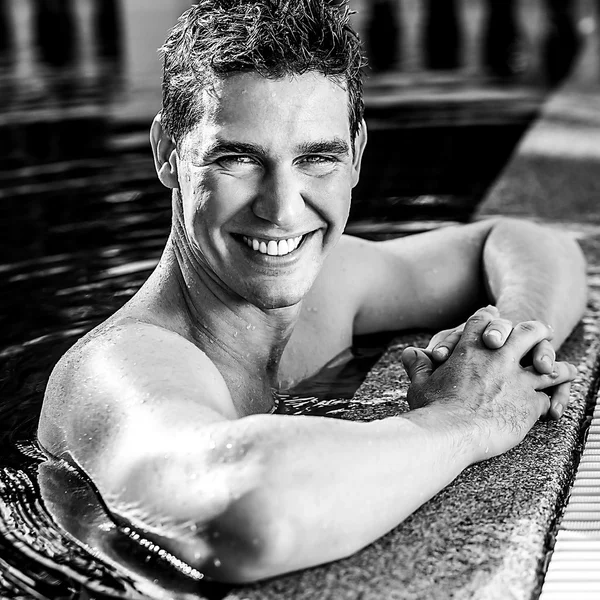 Handsome underwear man posing in swimming pool. Black-white photo.