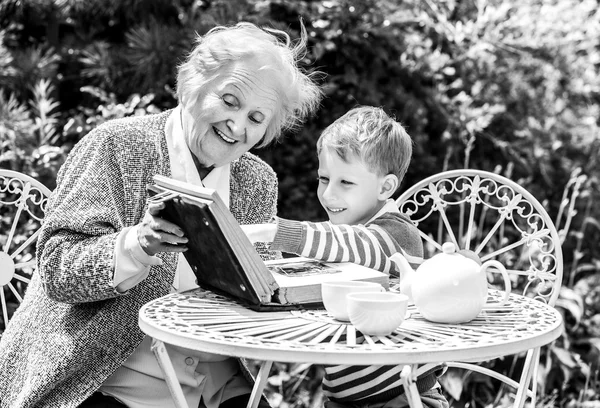 Positive grandmother and grandson spent time together in summer solar garden. Black-white photo.