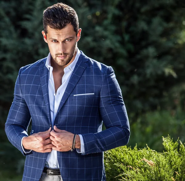 Elegant handsome man in classical jacket poses outdoor