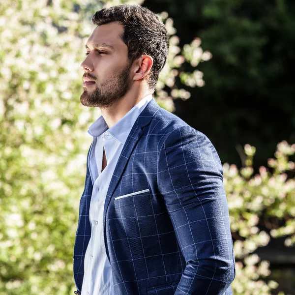 Elegant handsome man in classical jacket poses outdoor