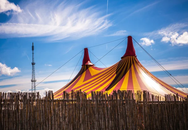Big top circus tent on a field in a park.