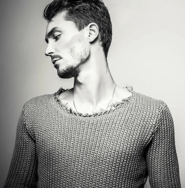 Black-white studio portrait of young handsome man in knitted sweater. Close-up photo.