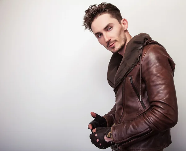 Attractive young man in a brown leather jacket pose in studio.