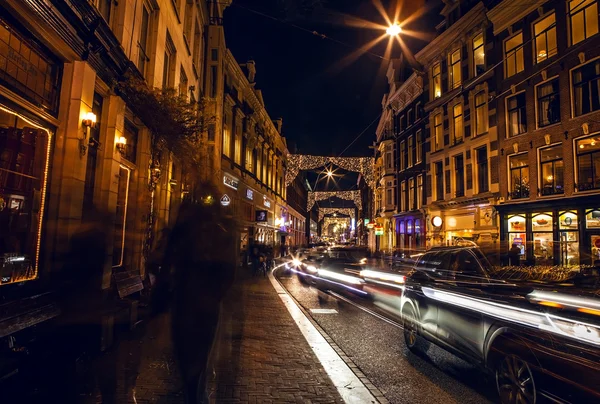 Headlights car passing down street in night Amsterdam.
