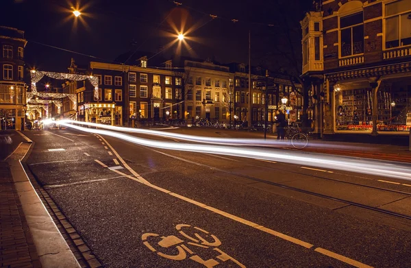Headlights car passing down street in night Amsterdam.