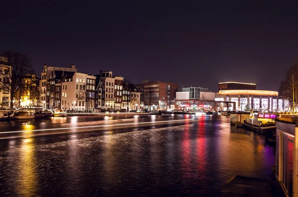 Cruise boat with blur light moving on night canals of Amsterdam.