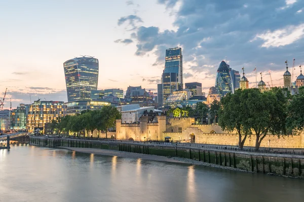 London, UK. City buildings along Thames river at dusk