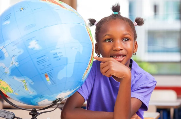 African girl at school with earth globe in background, geography