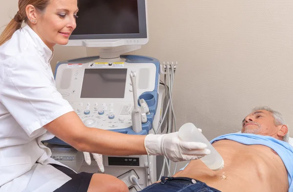 Mature man undergoing belly ultrasound with female doctor