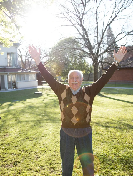 Happy retired man in the garden with hands up. Happiness concept