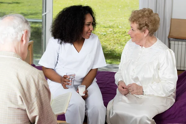 Nurse in rehab facility speaking to elder patients