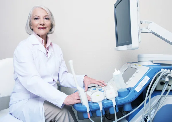 Senior female doctor smiling while setting up ultrasound machine