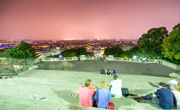 Tourists in Montmartre steps enjoying Paris night skyline