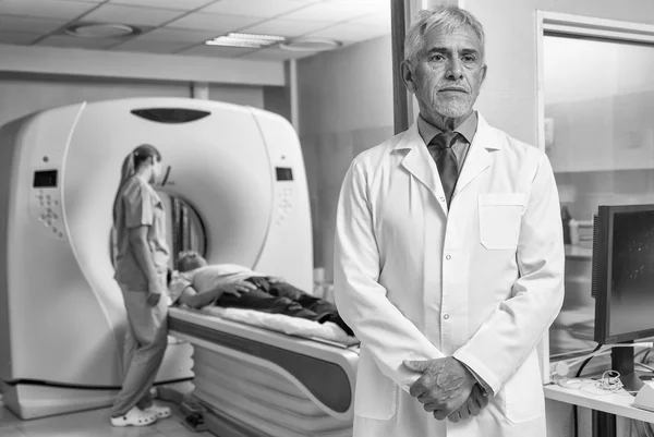 Confident male doctor in hospital with patient undergoing mri