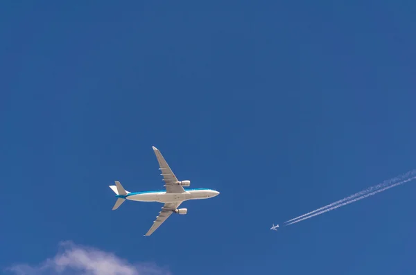 Two airplanes in the sky crossing paths at different flight trav