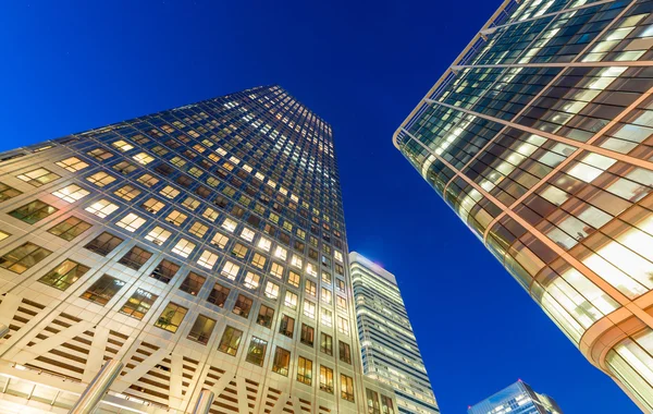 Skyward view of office buildings at night against blue sky