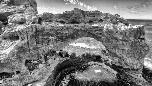 Black and white aerial view of The Arch along Great Ocean Road,