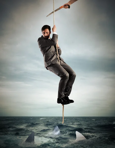 Man hanging from a rope cut by a saw