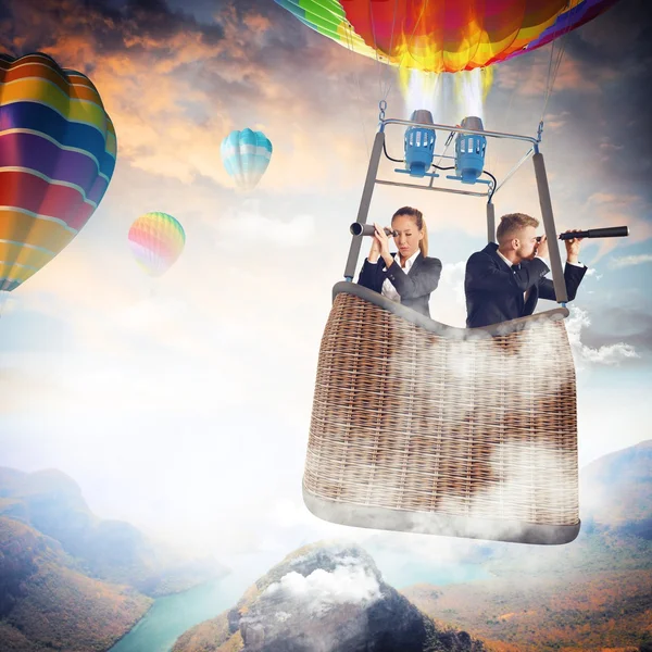 Business people with binoculars in hot air balloon