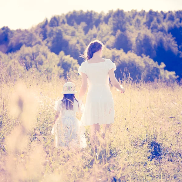 Mother and daughter walking on the meadow.